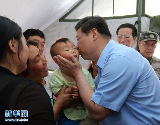 2013年5月21日，习近平在芦山县体育馆安置点一帐篷内亲抚一小孩。新华社记者兰红光摄